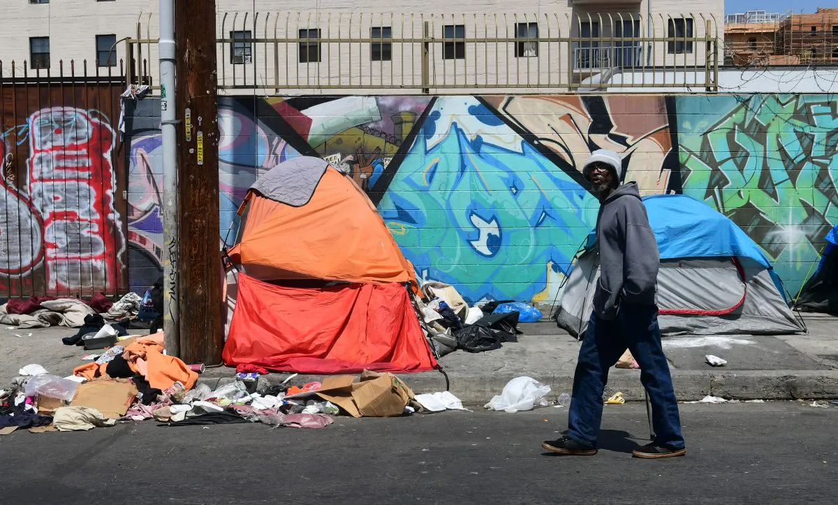 A pedestrian walks past tents and trash on a sidewalk in downtown Los Angeles on May 30, 2019. (Frederic J. Brown/AFP/Getty Images)