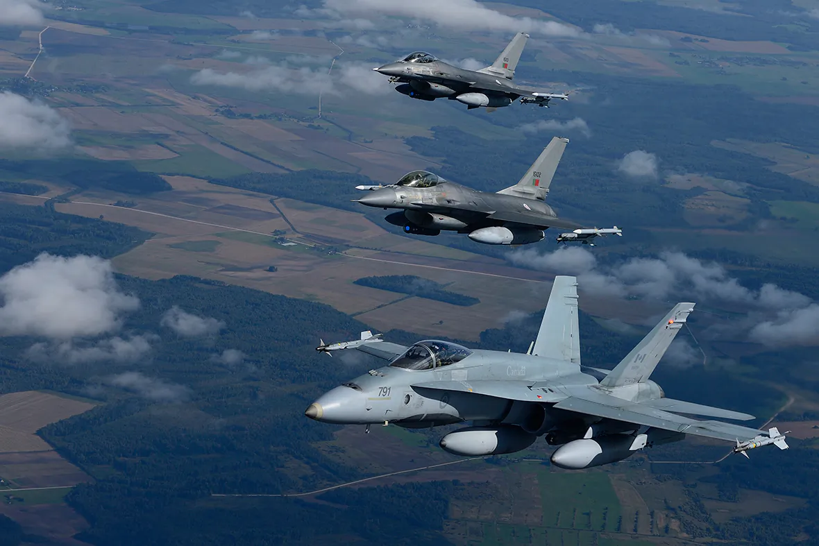 A CF-18 Hornet from the Canadian Air Task Force Lithuania flies beside two Portuguese F-16 Fighting Falcons over Lithuania for the NATO Baltic Air Policing Block 36 mission during Operation Reassurance on Sept. 15, 2014. (Canadian Armed Forces)