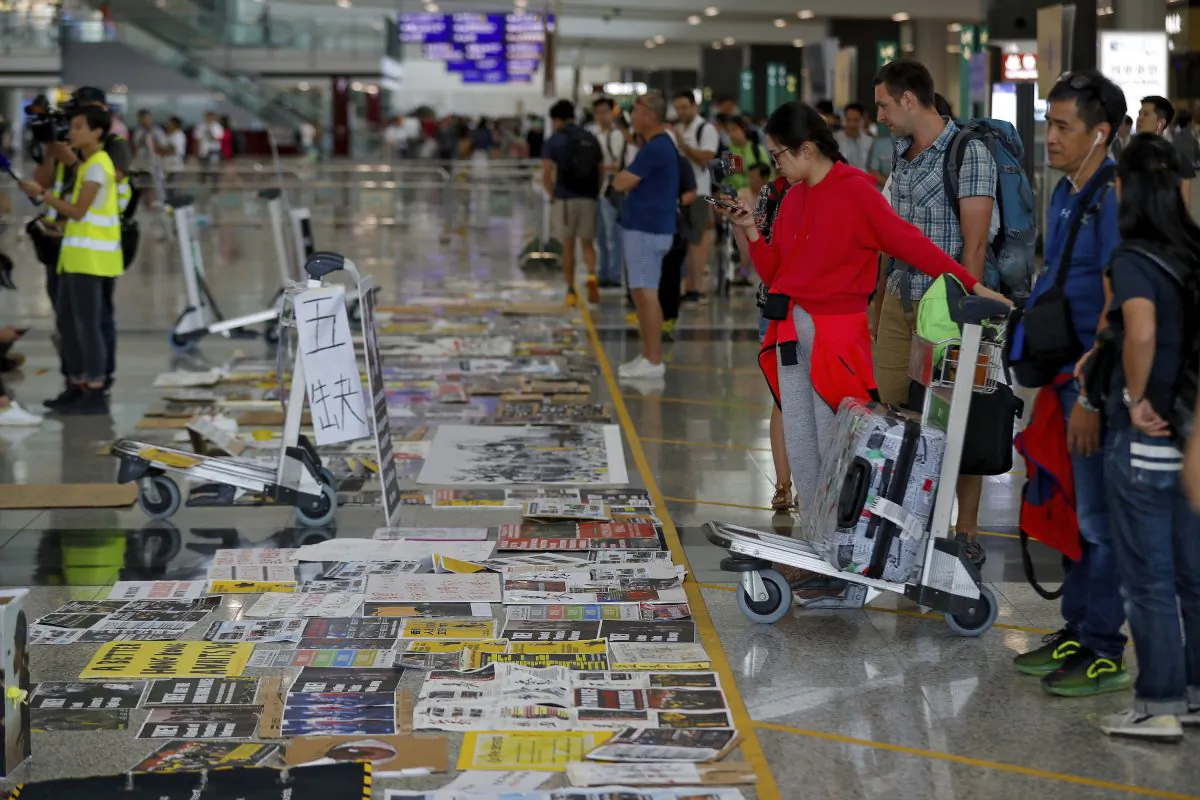 Traveller look at placards and posters placed by protesters at the airport in Hong Kong, China on Aug. 14, 2019. (Vincent Thian/AP)