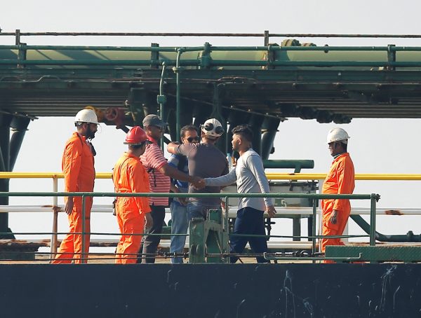 Two men are welcomed by crew members after embarking Iranian oil tanker Grace 1 as it sits anchored awaiting a court ruling 