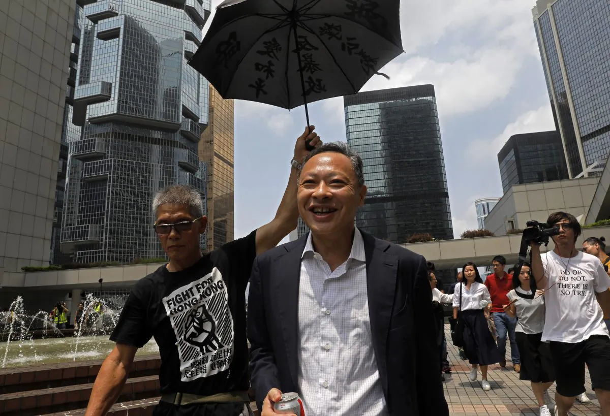 Occupy Central leader Benny Tai, center, is accompanied by a supporter who raises an umbrella as he leaves High court in Hong Kong on Aug.15, 2019. Tai, a top opposition leader imprisoned on public disorder charges was released on bail. (Vincent Yu/AP)