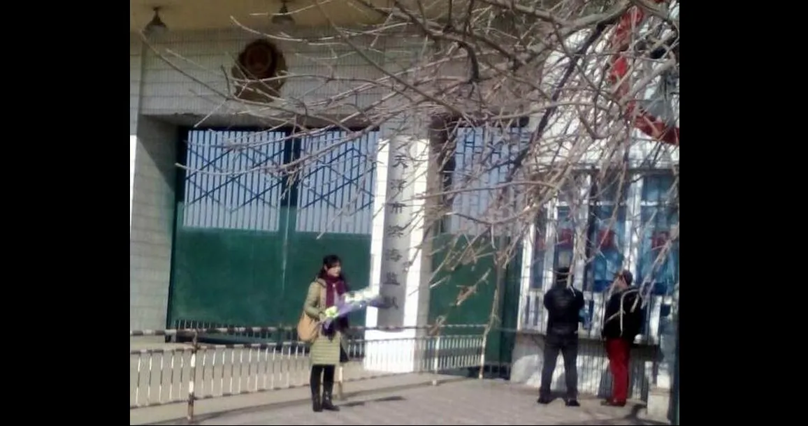 Ge Xiulan stands outside Binhai Prison holding flowers for her incarcerated husband on his birthday in 2018. Prison authorities didn’t allow her to visit him that day. (Minghui.org)