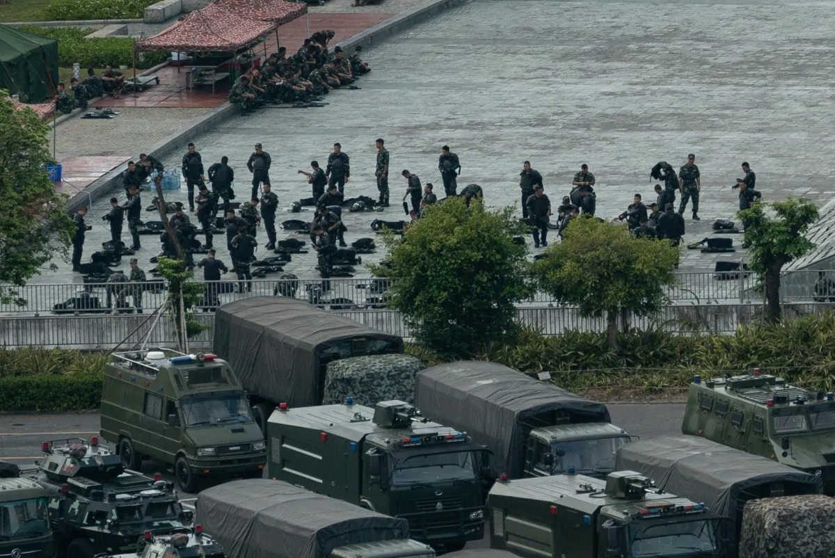 Chinese military personnel maintain trucks and armoured personnel vehicles parked outside the Shenzhen Bay stadium on August 16, 2019 in Shenzhen, China. (STR/AFP/Getty Images)