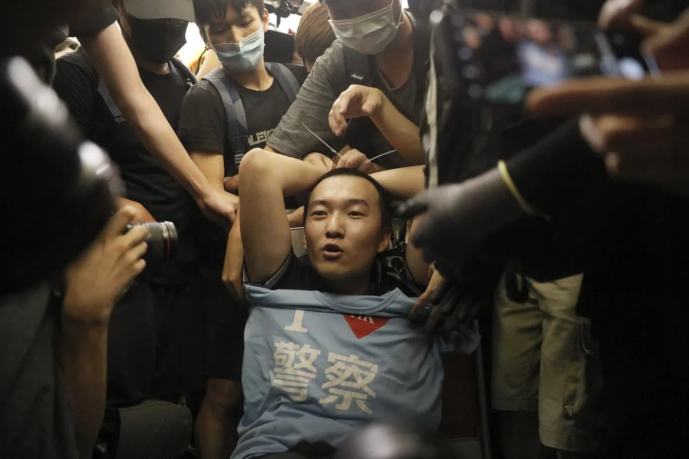 Protesters surround a man who was carrying a t-shirt bearing the words "I love police" during a demonstration at the Hong Kong airport, on Aug. 13, 2019. Protesters claimed he was a police officer from mainland China. (AP Photo/Vincent Yu)