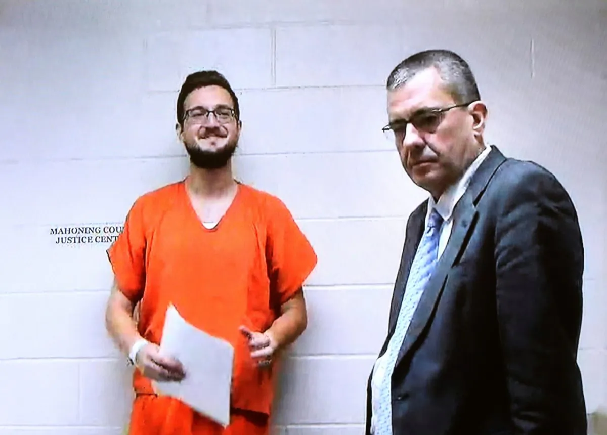 James Reardon, of New Middletown, Ohio, stands with attorney Walter Richie at the jail, seen on the video arraignment for Reardon at Struthers Municipal Court in Struthers, Ohio, on Aug. 19, 2019. (Robert K. Yosay/The Vindicator via AP)