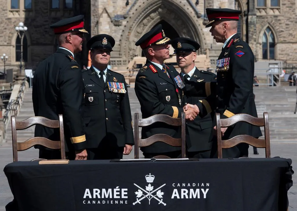 Chief of Defence Staff Jonathan Vance shakes hands with Lieutenant-General Wayne Eyre as he assumes command of the Canadian Army from Lieutenant-General Jean-Marc Lanthier (left) as Chief Warrant Officer Alain Gumond (second from left) and CWO Stuart Hartnell look during a change of command parade on Parliament Hill, August 20, 2019 in Ottawa. (Adrian Wyld/The Canadian Press)