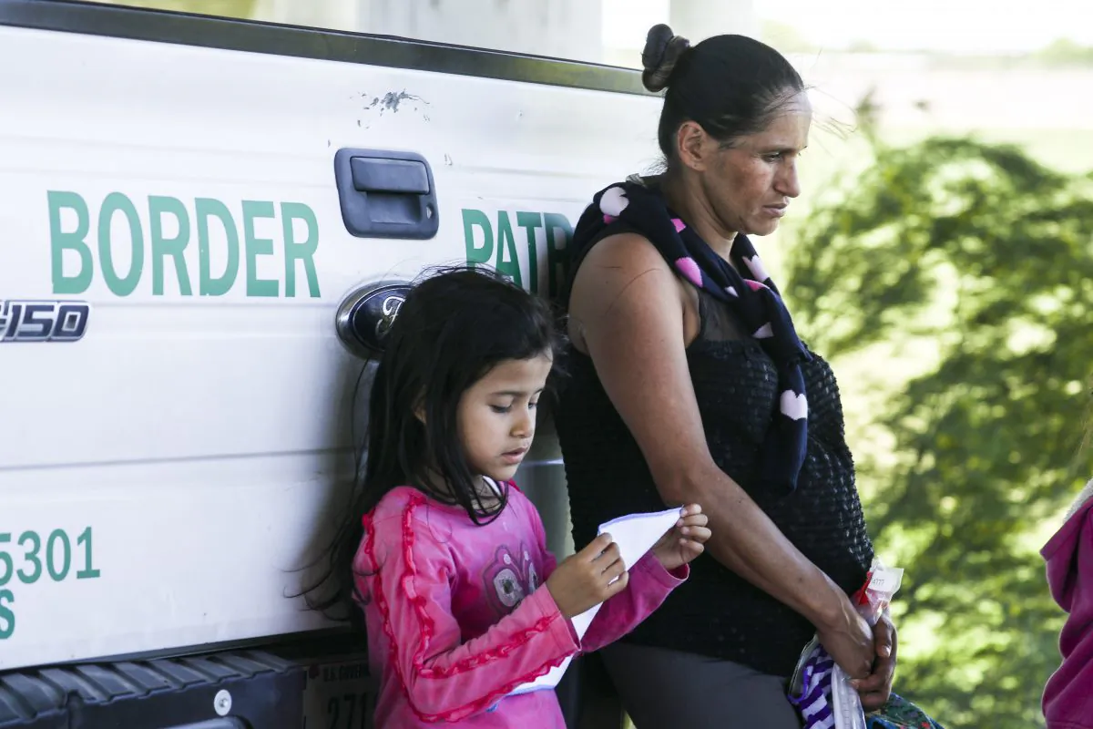 A heavily pregnant woman and a girl lean against a Border Patrol truck after being apprehended for illegally crossing the U.S. border over the Rio Grande from Mexico near McAllen, Texas, on April 18, 2019. (Charlotte Cuthbertson/The Epoch Times)