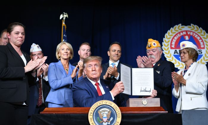 President Donald Trump sign a Presidential Memorandum on Discharging the Federal Student Loan Debt of Totally and Permanently Disabled Veterans, at the American Veterans 75th National Convention in Louisville, Kentucky, on Aug. 21, 2019. (MANDEL NGAN/AFP/Getty Images)