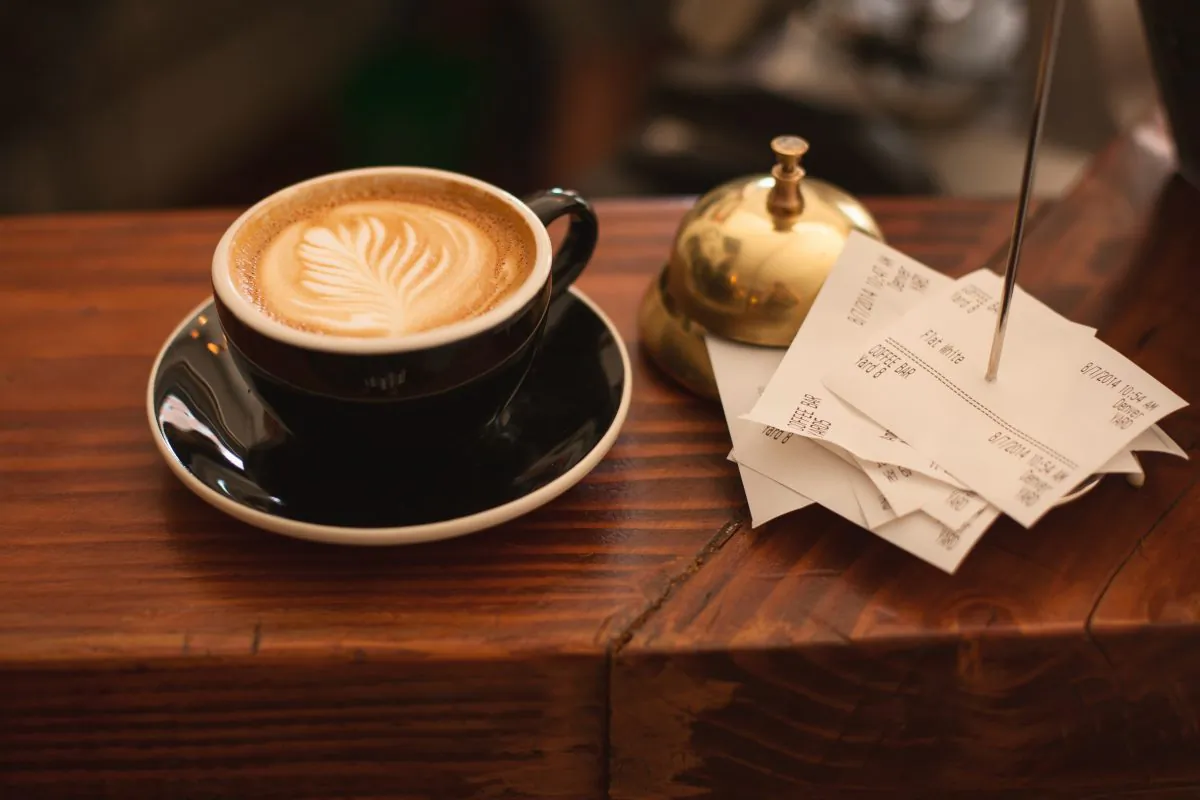 Stock photo of a cup of coffee and some receipts at a restaurant. (Carli Jeen/Unsplash)