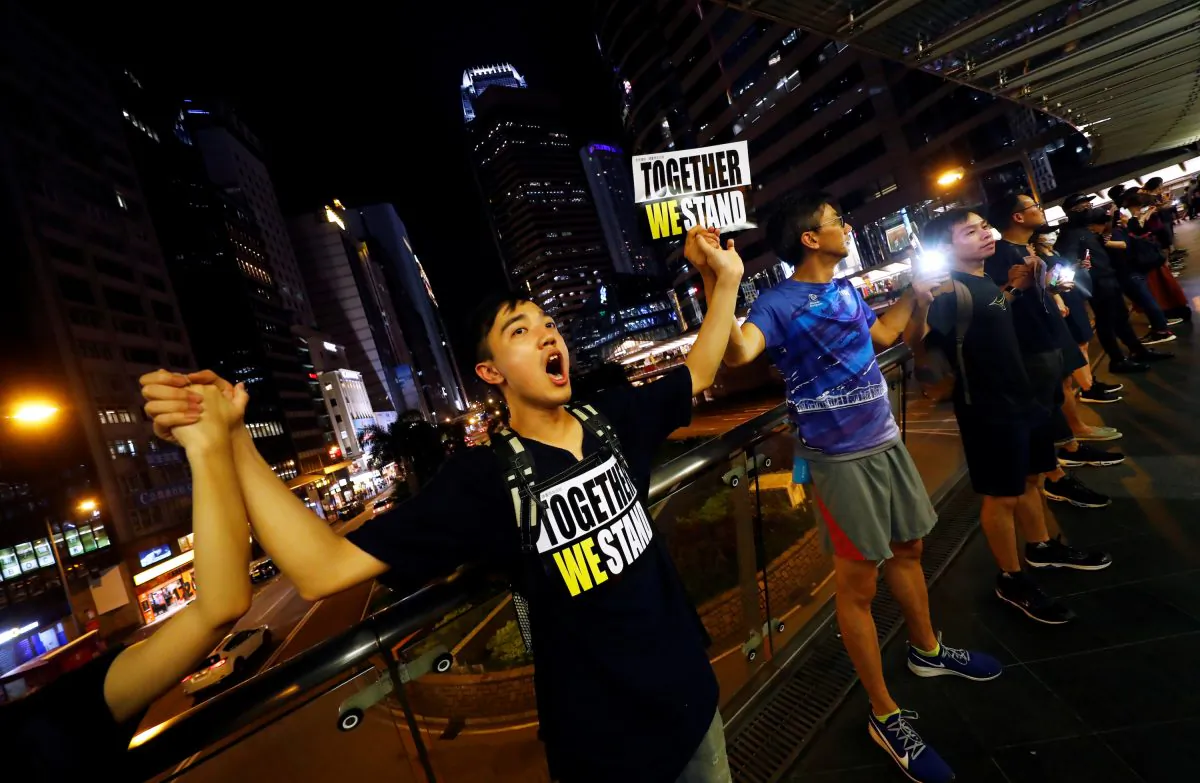 Protesters hold hands to form a human chain during a rally to call for political reforms in Hong Kong's Central district, China on Aug. 23, 2019. (Kai Pfaffenbach/Reuters)