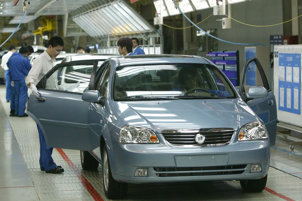Workers work at a product line of Buick Excelles at Jinqiao South Vehicle Plant of Shanghai General Motors Corp. in Shanghai, China on May 28, 2005. (China Photos/Getty Images)