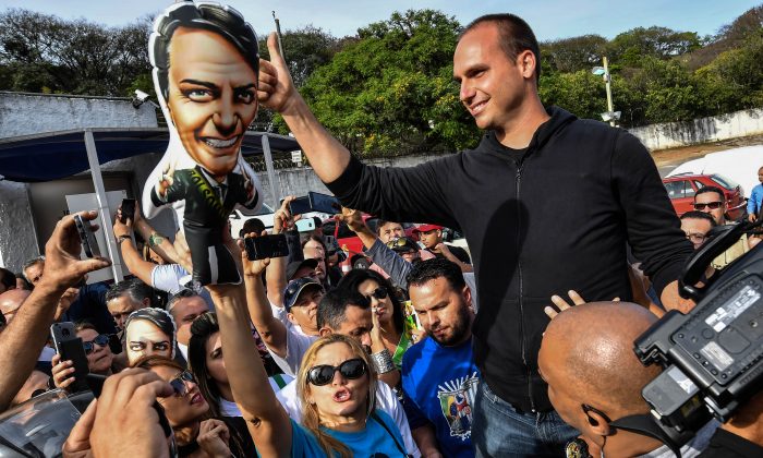 The son of Brazilian right-wing presidential candidate Jair Bolsonaro, Eduardo Bolsonaro, gives his thumb up to his father's supporters gathering in front of the Israelita Albert Einstein Hospital in Sao Paulo, Brazil, on September 16, 2018 after it was announced that their stabbed leader left the intensive care unit. - Brazil presidential election front-runner Bolsonaro was stabbed by a left-wing activist on September 6 during a campaign rally in the southern state of Minas Gerais. (Photo by Nelson ALMEIDA / AFP)        (Photo credit should read NELSON ALMEIDA/AFP/Getty Images)