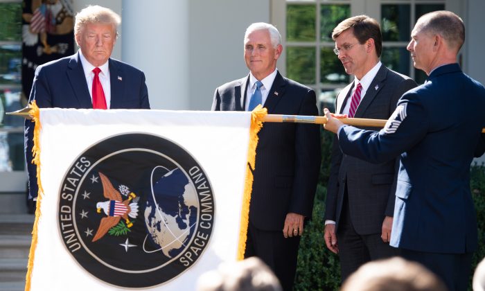 A member of the US military unfurls the new U.S. Space Command flag alongside President Donald Trump (L), Vice President Mike Pence (2nd L) and Secretary of Defense Mark Esper during an event establishing the US Space Command in the Rose Garden of the White House on Aug. 29, 2019. (Saul Loeb/AFP/Getty Images)