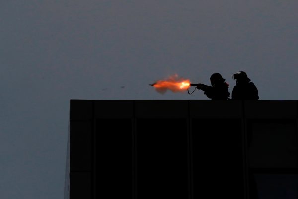 Riot police fires tear gas from the balcony of the government headquarters building to disperse protesters.