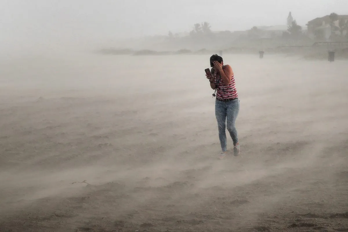 A woman seeks cover from wind, blowing sand, and rain whipped up by Hurricane Dorian as she walks on the beach in Cocoa Beach, Florida, on Sept. 2, 2019. (Scott Olson/Getty Images)