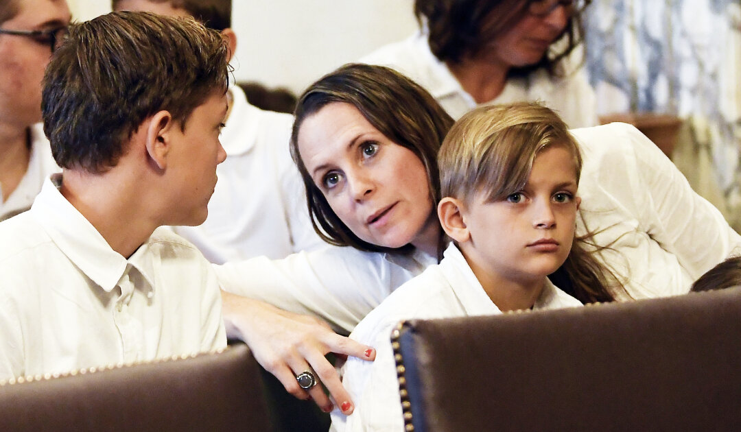 Leslie Danesi, center, sits with her children Lorenzo Danesi, left, and Gabriel Danes, right, as attorneys prepare to speak at a hearing challenging the constitutionality of the state legislature's repeal of the religious exemption to vaccination in Albany, N.Y. on Aug. 14, 2019.
