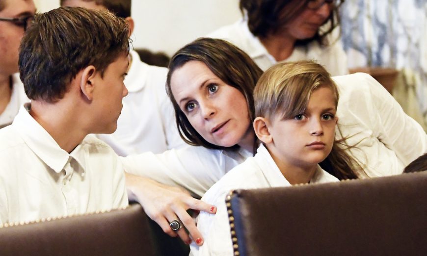 Leslie Danesi, center, sits with her children Lorenzo Danesi, left, and Gabriel Danes, right, as attorneys prepare to speak at a hearing challenging the constitutionality of the state legislature's repeal of the religious exemption to vaccination in Albany, N.Y. on Aug. 14, 2019.
