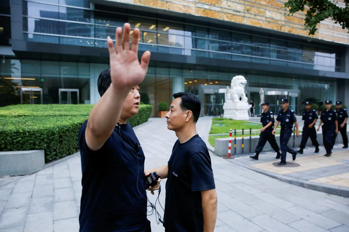 A police officer gestures at the photographer as security patrol outside the headquarters of China Banking and Insurance Regulatory Commission in Beijing, China, on Aug. 6, 2018. (Thomas Peter/Reuters)