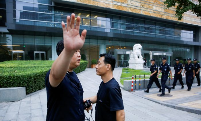A police officer gestures at the photographer as security patrol outside the headquarters of China Banking and Insurance Regulatory Commission in Beijing, China, on Aug. 6, 2018. (Thomas Peter/Reuters)