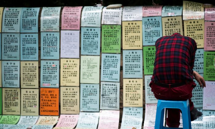 A Chinese man sleeps in front of advertising notices, placed there by parents of people looking for partners at a marriage market in Shanghai, China, on May 30, 2015. (Johannes Eisele/AFP/Getty Images)
