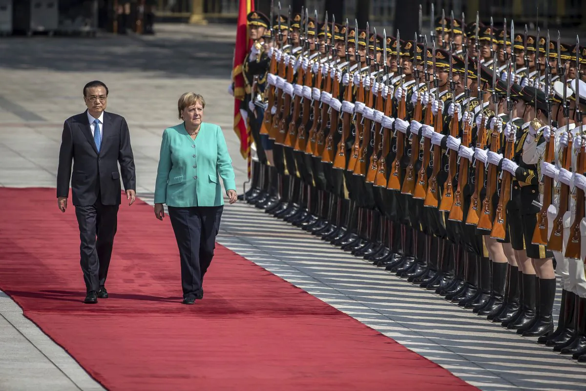 Chinese Premier Li Keqiang (L) and German Chancellor Angela Merkel (C) inspect an honor guard during a welcome ceremony at the Great Hall of the People in Beijing, China on Sept. 6, 2019. (Roman Pilipey/Pool Photo via AP)