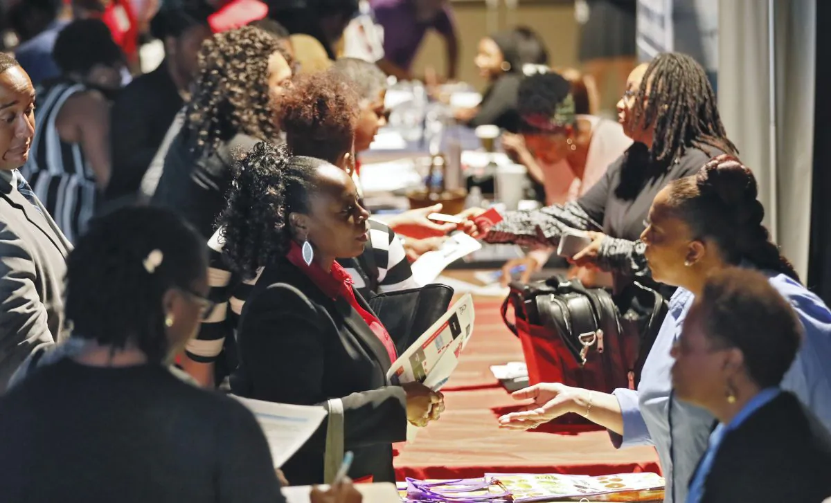 Company representatives from Verizon, Goodwill, Kaiser Permanente, and UPS, right, talk with potential applicants during a job and resource fair in Atlanta, Ga., in a file photo. (Bob Andres/Atlanta Journal-Constitution via AP)