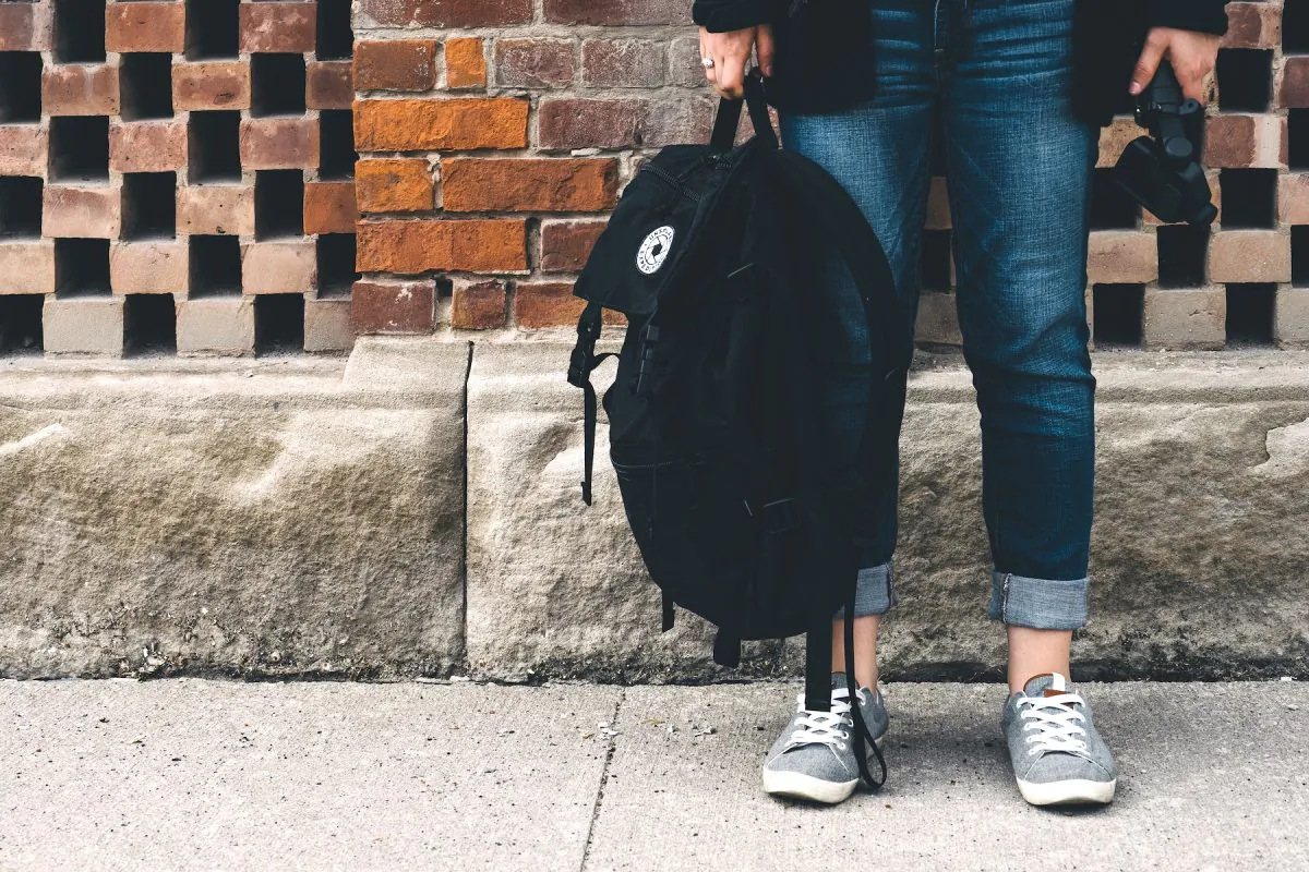 Illustration photo of person holding backpack. (@scottwebb/Unsplash)