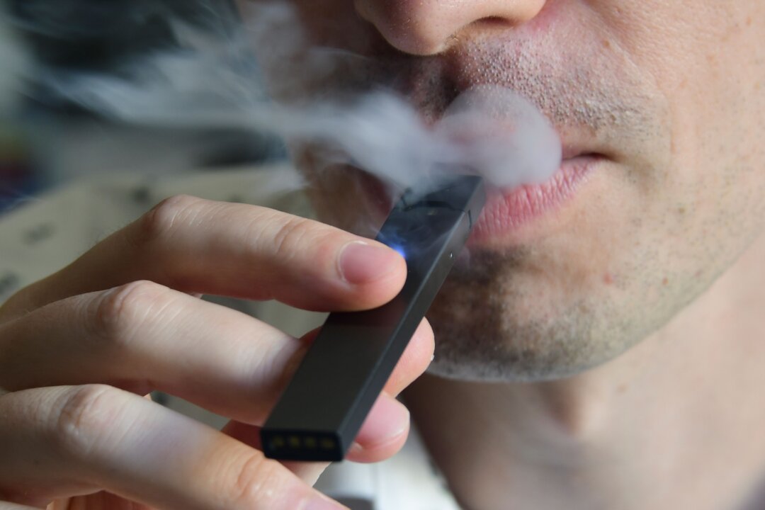 An illustration shows a man exhaling smoke from an electronic cigarette. (Eva Hambach/AFP/Getty Images)