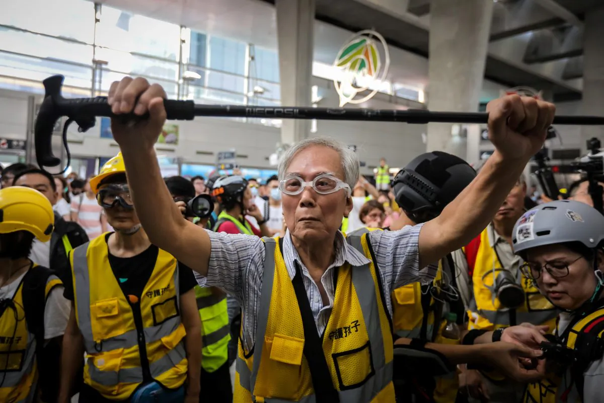 "Grandpa Wong" (C), 85, shielding protesters from the police by holding his walking stick up, along with other "Protect Our Kids" volunteers in the Tung Chung district in Hong Kong, on September 7, 2019. (VIVEK PRAKASH/AFP/Getty Images)