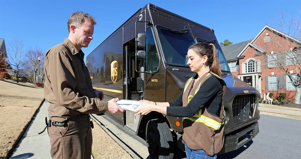 A young seasonal worker (R) helps deliver a parcel for UPS. (Courtesy of UPS)