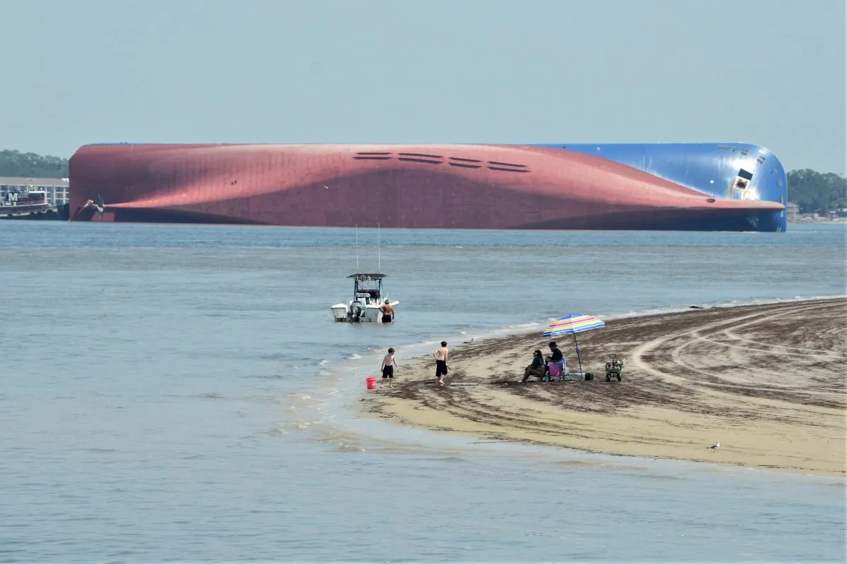 People are shown on Jekyll Island's Driftwood Beach as the Golden Ray cargo ship is capsized in the background, off the Georgia coast, on Sept. 8, 2019. (Terry Dickson/AP Photo)