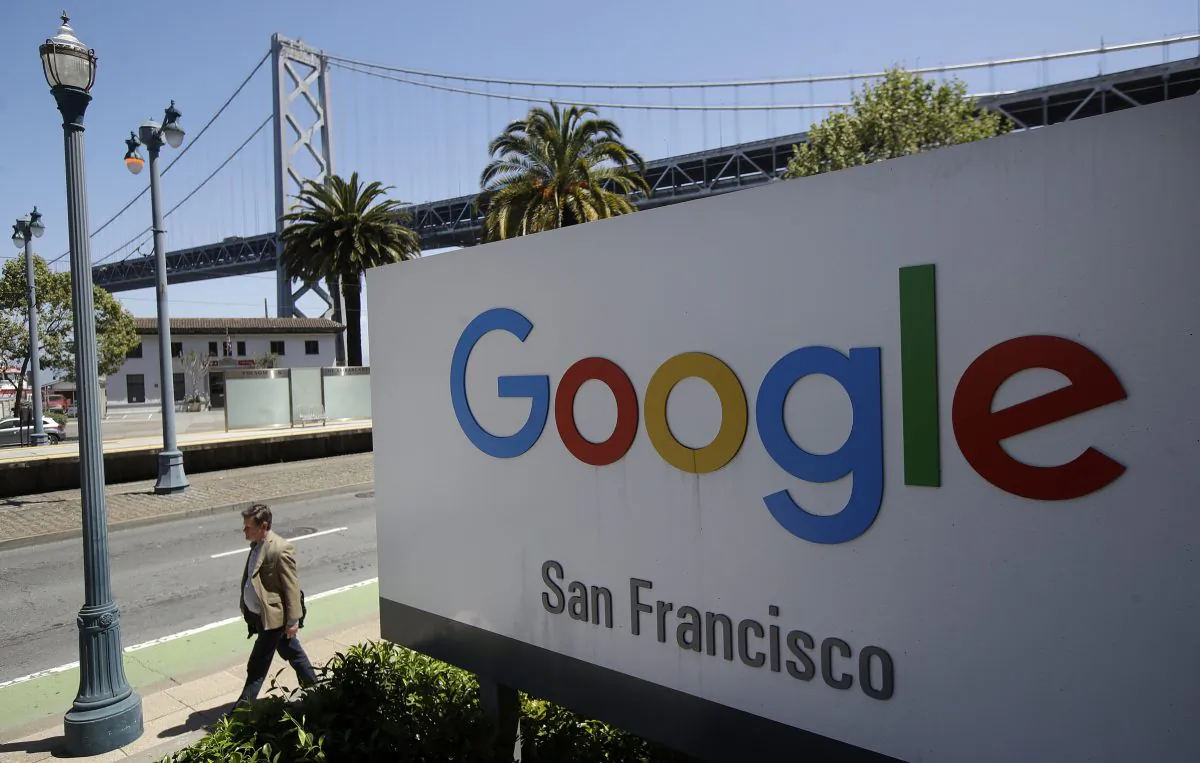 A man walks past a Google sign outside with a span of the Bay Bridge at rear in San Francisco on May 1, 2019. (Jeff Chiu/AP Photo)