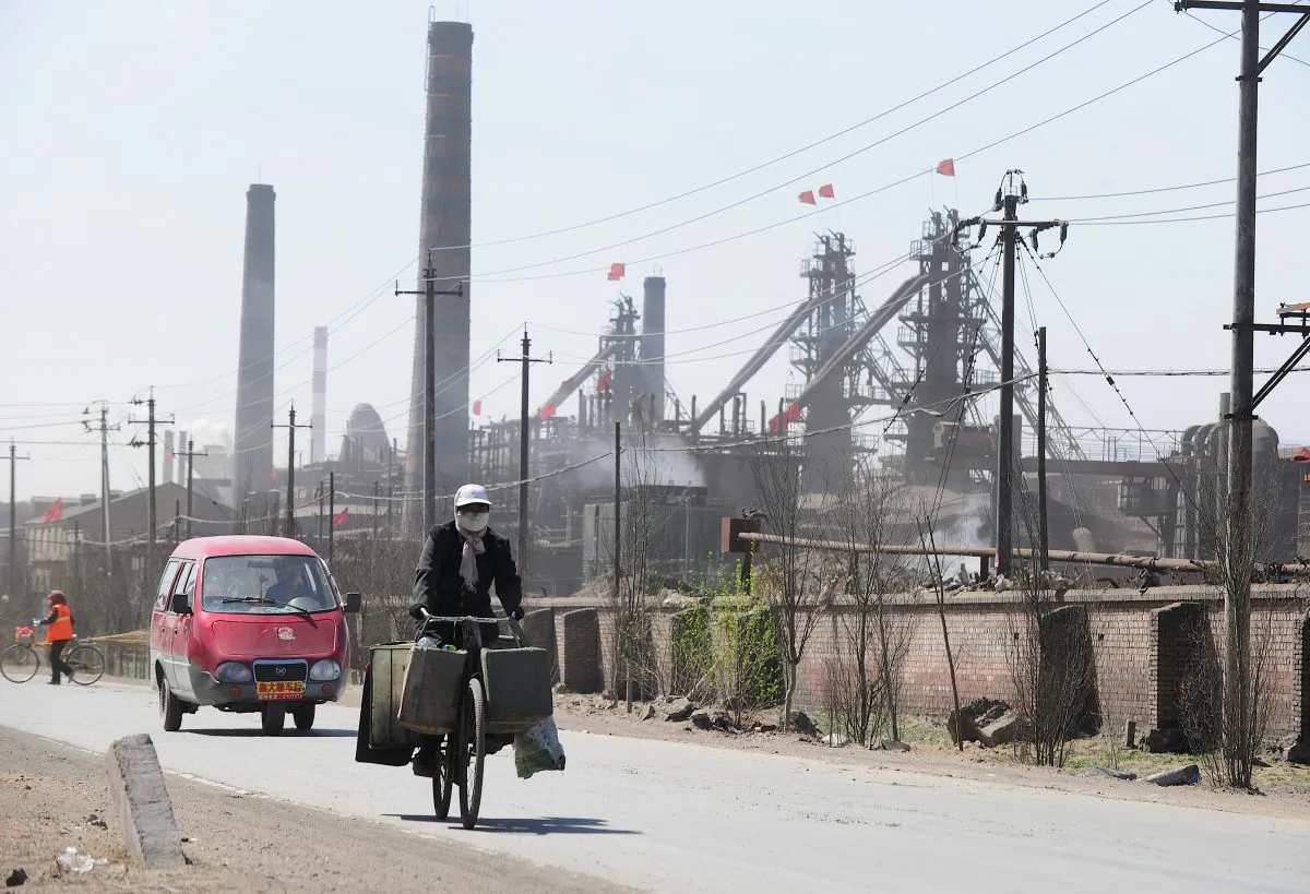 In a file photo taken on April 21, 2011, a cyclist wears a protective face mask while riding along a dusty road where dozens of factories processing rare earths, iron and coal operate on the outskirts of Baotou city in Inner Monglia, northwest China. (Frederic J. Brown/AFP/Getty Images)
