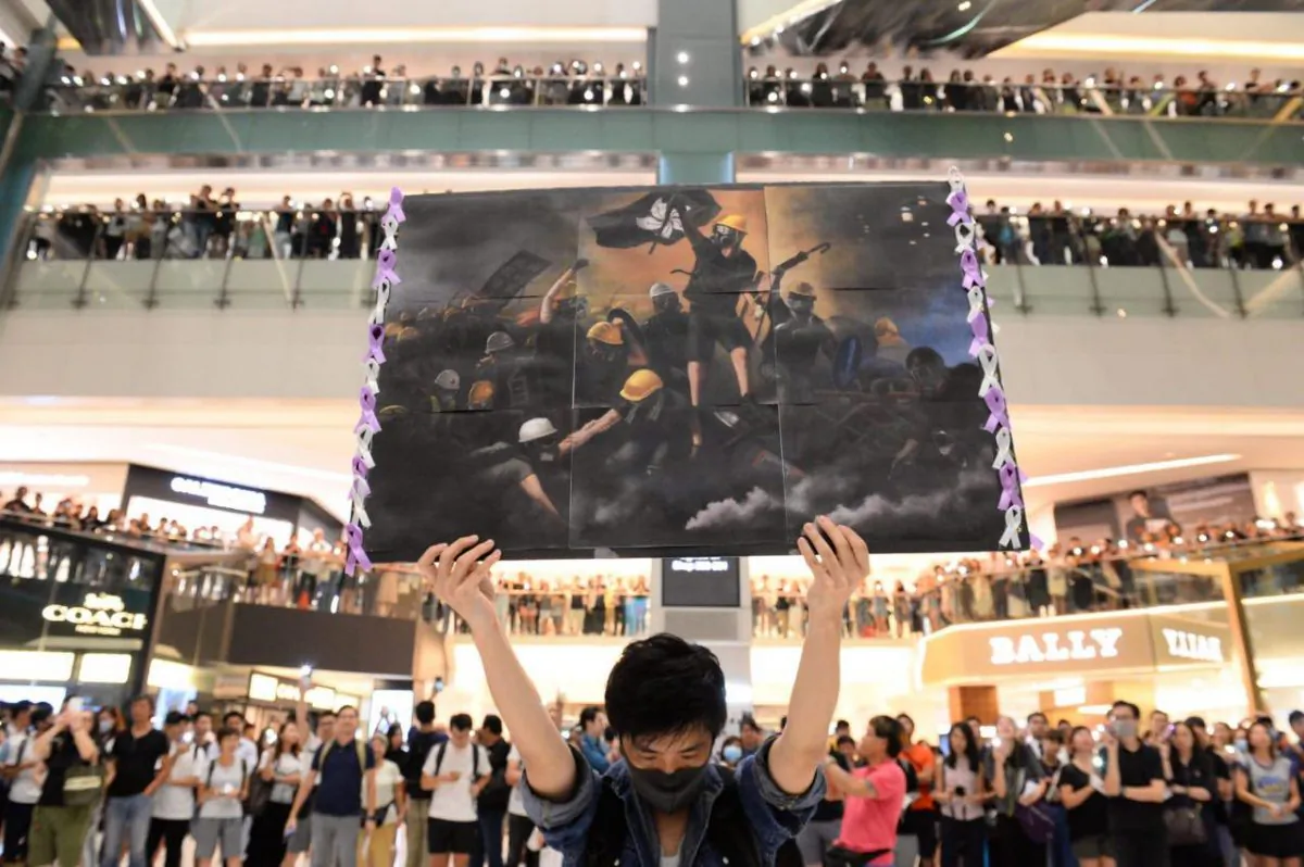 A man holds a poster at a shopping mall in the Sha Tin area of Hong Kong on Sept. 11, 2019, to sing a recently penned protest song titled 'Glory to Hong Kong which has been gaining popularity in the city. (Huang Xiaoxiang/The Epoch Times)