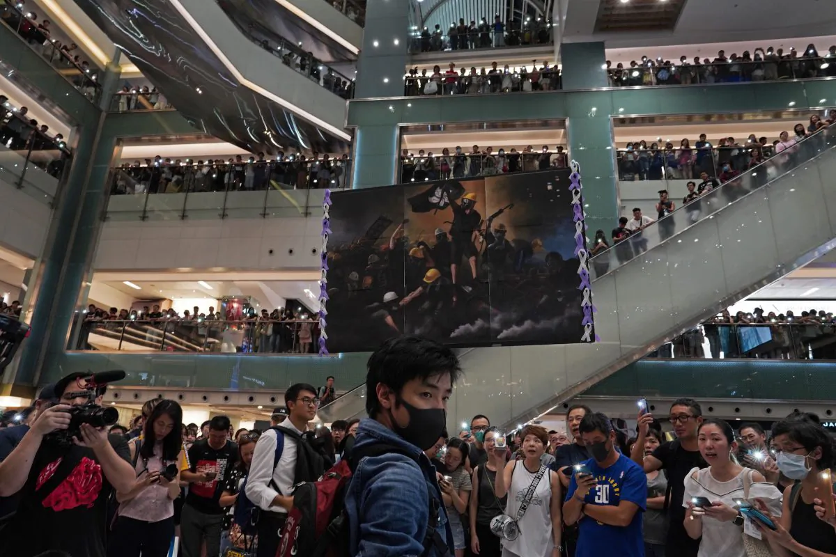 A protester raises a painting of protesters after they sing a theme song written by protesters "Glory be to thee" at a shopping mall in Hong Kong, China on Sept. 11, 2019. (Vincent Yu/AP)