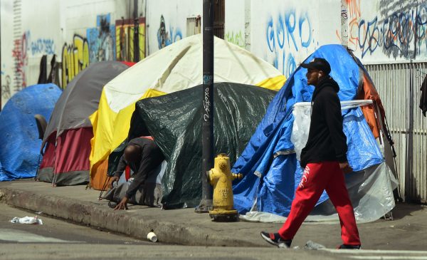 A homeless person walks by a tent