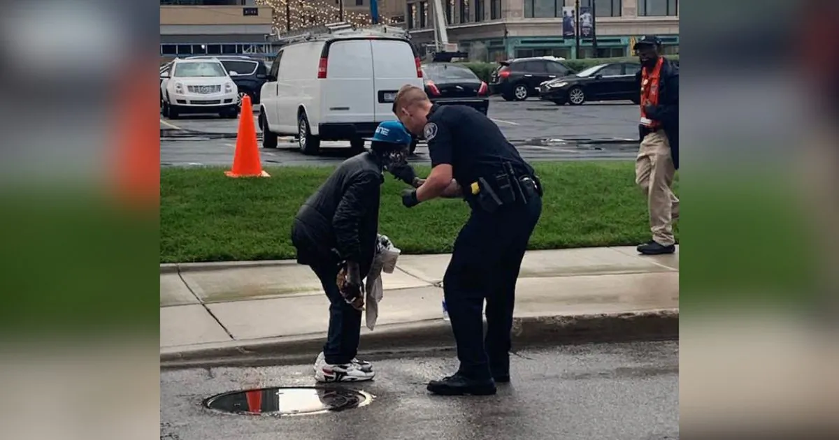 A police officer helps a man shave outside of Comerica Park in Detroit, Michigan, on Sept. 11, 2019. (Courtesy of Jill Metiva Schafer)