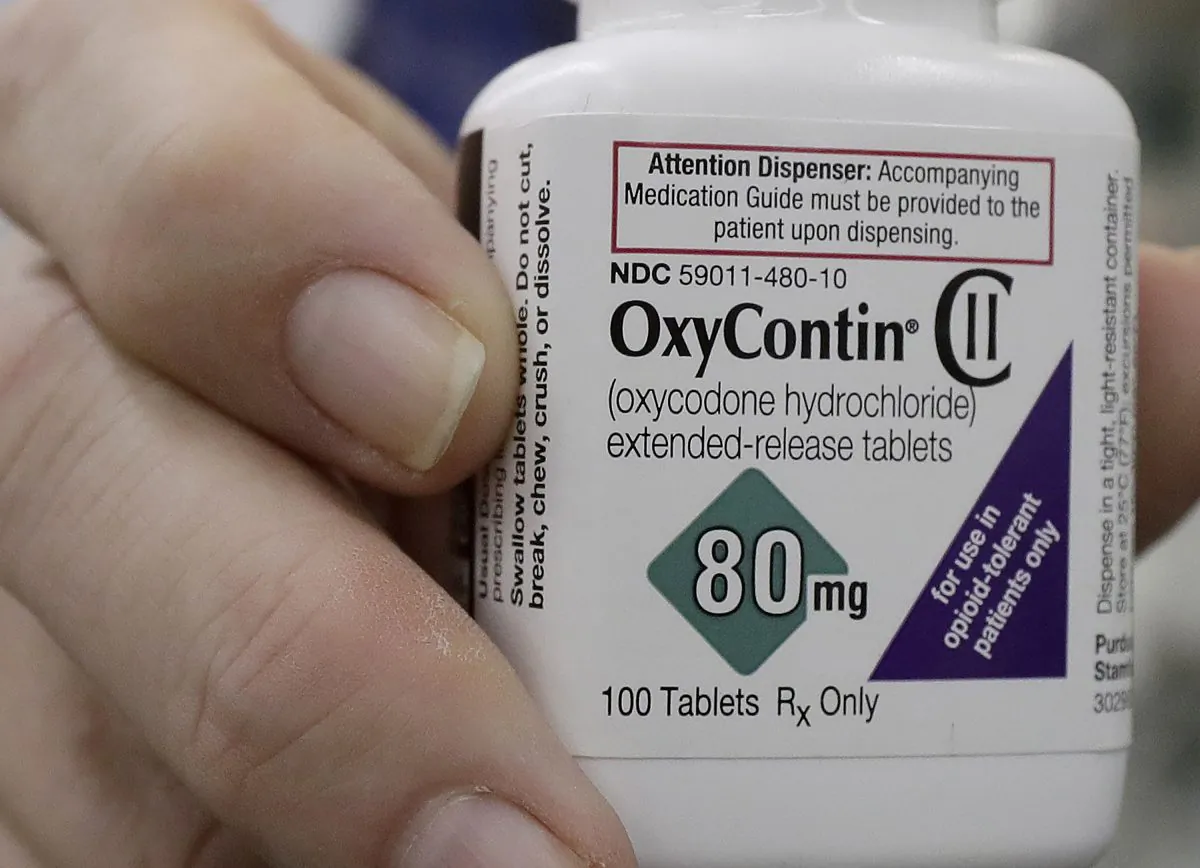 A pharmacist in San Francisco poses for photos holding a bottle of OxyContin on April 2, 2018. (Jeff Chiu AP Photo)