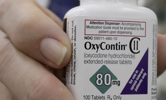 2018 年 4 月 2 日，旧金山的一名药剂师拿着一瓶 OxyContin 摆姿势拍照。（Jeff Chiu 美联社照片）