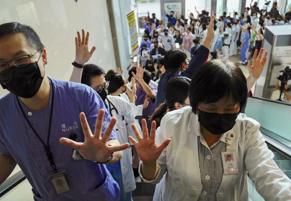 Medical workers display their palm with five fingers, signifying the five demands of protesters and chanted slogans as they stood in the foyer of the hospital before moving to different floors of the building at the Prince of Wales Hospital in Hong Kong on Sept. 16, 2019. (Vincent Yu/AP)