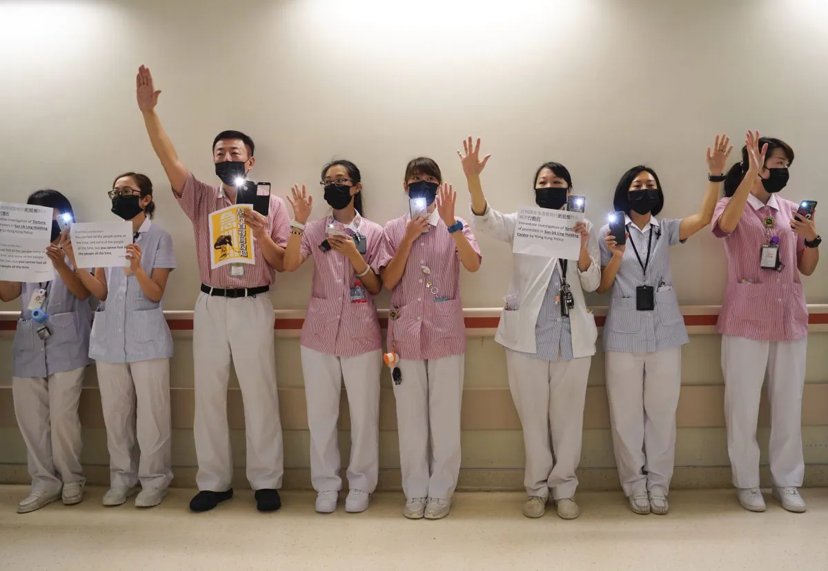 Medical workers display open palms with five fingers, signifying the five demands of protesters and chanting slogans as they stood in the foyer of the hospital before moving to different floors of the building at the Prince of Wales Hospital in Hong Kong, on Monday, Sept. 16, 2019. (AP Photo/Vincent Yu)