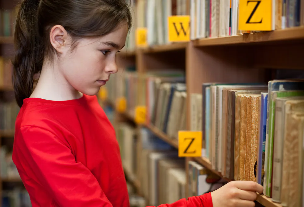 A child browses books in a library. (Shutterstock)