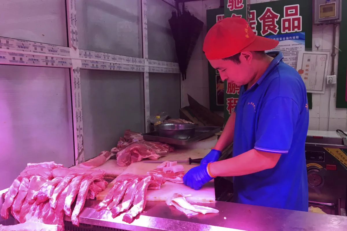 A butcher slices cuts of pork at a meat market in Beijing on Sept. 11, 2019. (Fu Ting/AP)