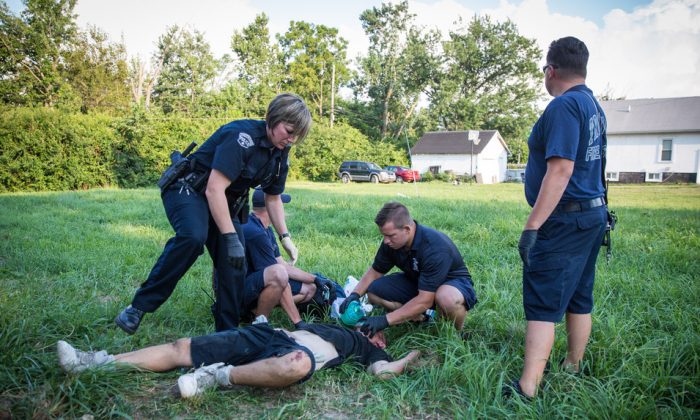 Local police and paramedics help a man who is overdosing in the Drexel neighborhood of Dayton, Ohio, on Aug. 3, 2017. It's unclear what he overdosed on. (Benjamin Chasteen/The Epoch Times)