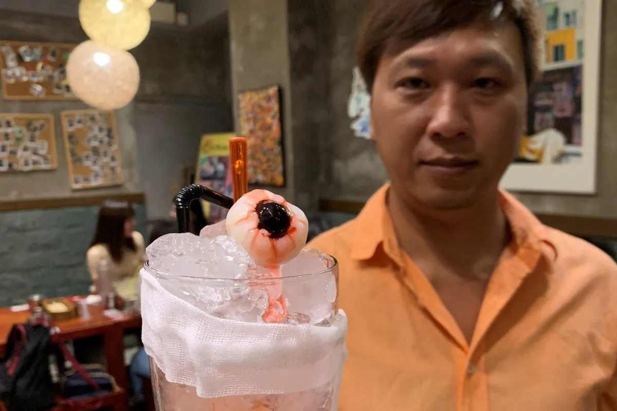 Spicy Andong owner Roy Ma poses with a glass of "eye for an eye," a blackcurrant longan soda with strawberry syrup, at his restaurant in Hong Kong, China on Sept. 19, 2019. (Vorasit Satienlerk/Reuters)