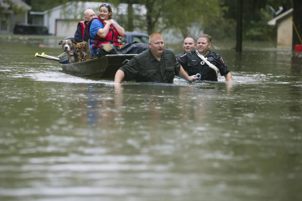 Splendora Police Lt. Troy Teller, left, Cpl. Jacob Rutherford, and Mike Jones pull a boat carrying Anita McFadden and Fred Stewart from their flooded neighborhood inundated by rain from Tropical Depression Imelda in Spendora, Texas, on Sept. 19, 2019. (Brett Coomer/Houston Chronicle via AP)