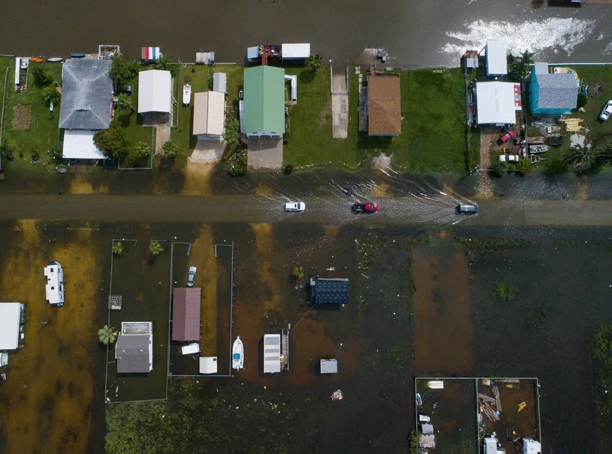 Cars drive on a flooded street in Sargent, Texas, as seen in this aerial photo Wednesday, Sept. 18, 2019.(Mark Mulligan/Houston Chronicle via AP)
