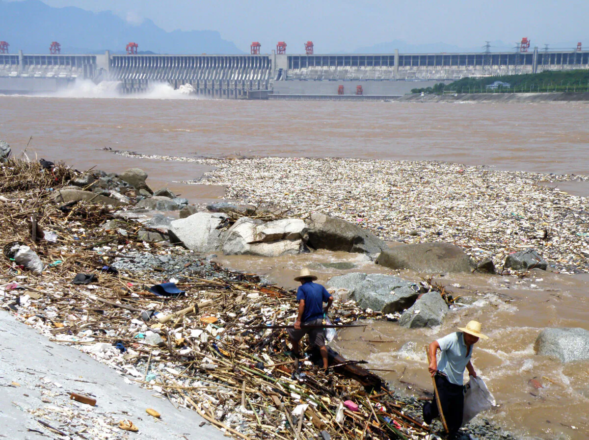 Two workers clean up trash along the bank of the Yangtze River near the Three Gorges Dam in Yichang, in central China's Hubei Province on Aug. 1, 2010. Layers of trash floating in the Yangtze River were threatening to jam China's massive Three Gorges hydroelectric dam, state media reported on Aug. 2. (China Out/STR/AFP/Getty Images)