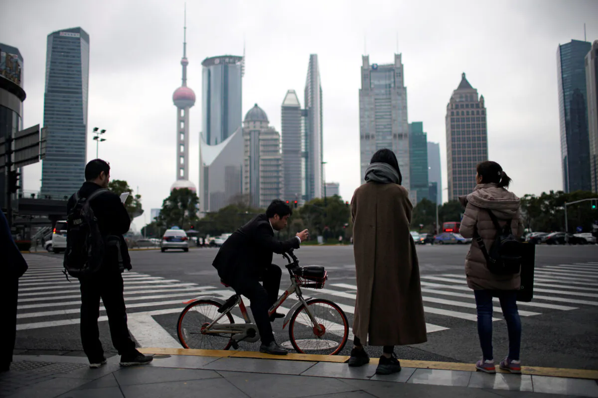 People stand on the sidewalk at Lujiazui financial district in Pudong, Shanghai, China on March 14, 2019. (Aly Song/Reuters)