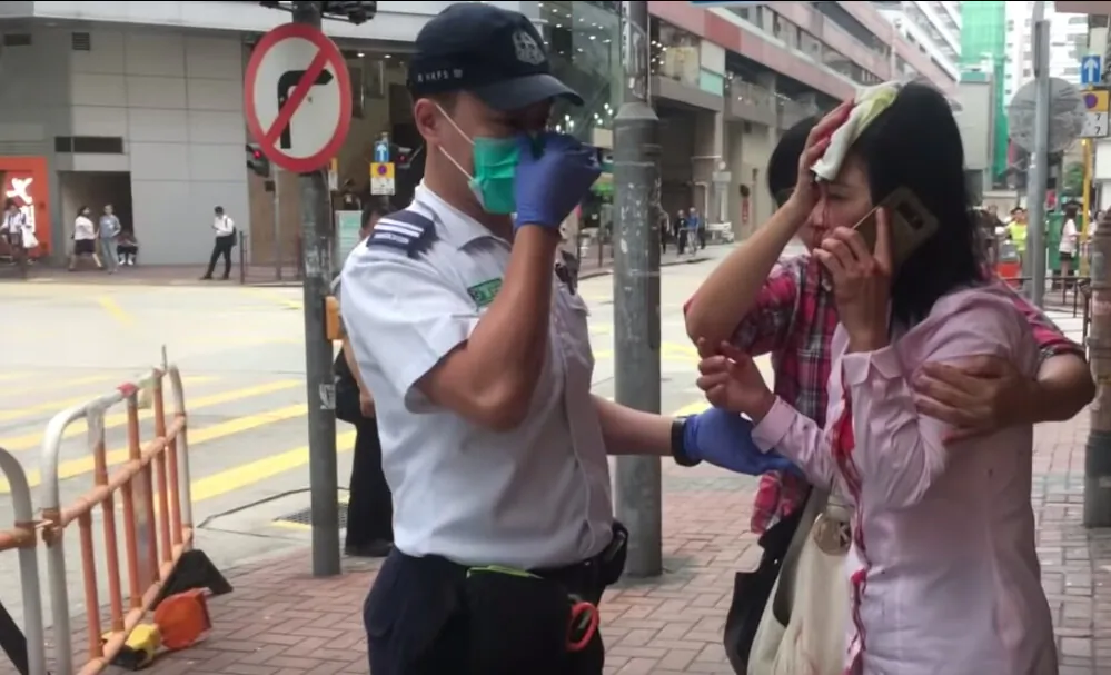 Liao Qiulan speaks with a police officer after being attacked by a man with a rod in Hong Kong on Sept. 24, 2019. (The Epoch Times)